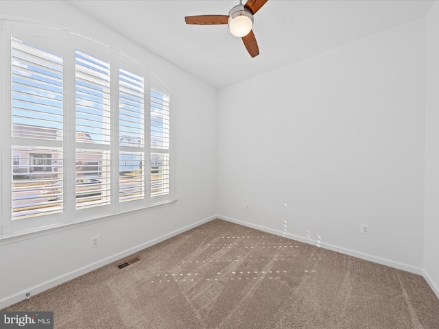 spare room with carpet floors, baseboards, visible vents, and ceiling fan