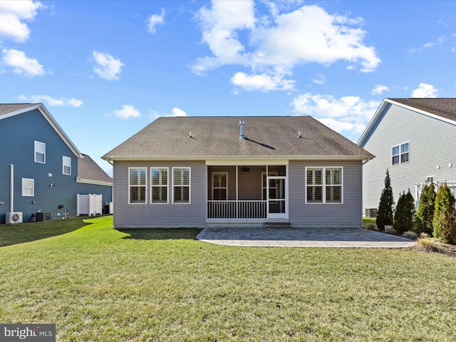 back of property with a yard, a sunroom, a patio, and a shingled roof