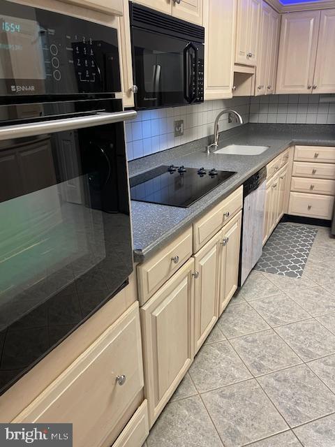 kitchen featuring tasteful backsplash, sink, light tile patterned floors, and black appliances