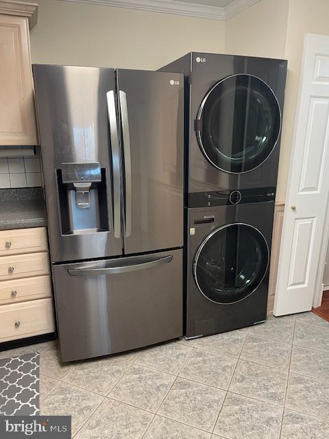 laundry room with crown molding, stacked washing maching and dryer, and light tile patterned flooring