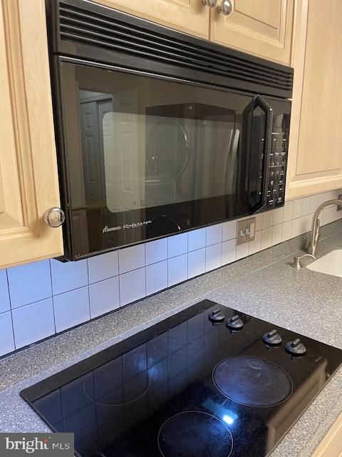 details featuring tasteful backsplash, sink, light brown cabinets, and black appliances