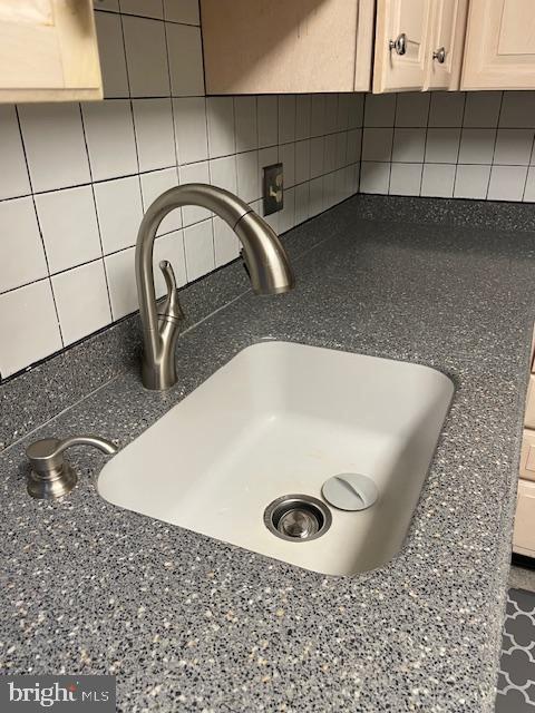 room details with dark stone countertops, sink, decorative backsplash, and light brown cabinets