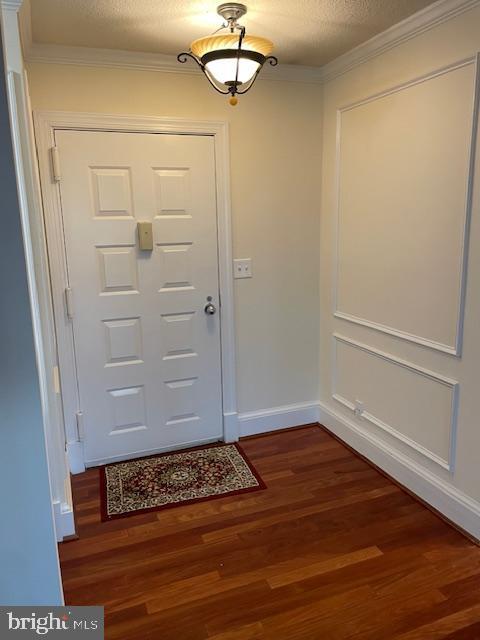 entryway with ornamental molding, dark hardwood / wood-style floors, and a textured ceiling