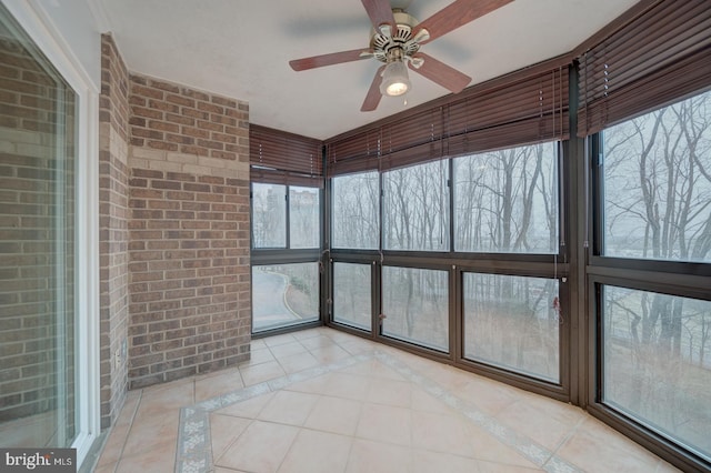 unfurnished sunroom featuring ceiling fan and a healthy amount of sunlight