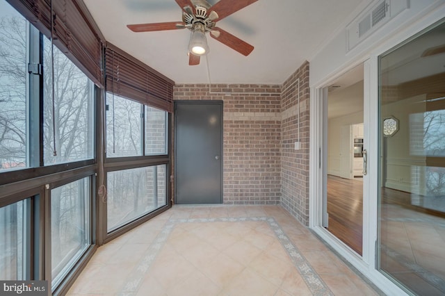 unfurnished sunroom featuring ceiling fan