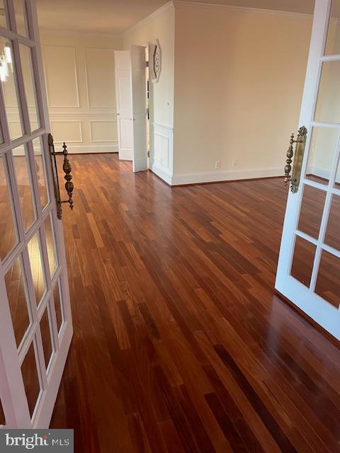 spare room featuring crown molding, dark hardwood / wood-style floors, and french doors