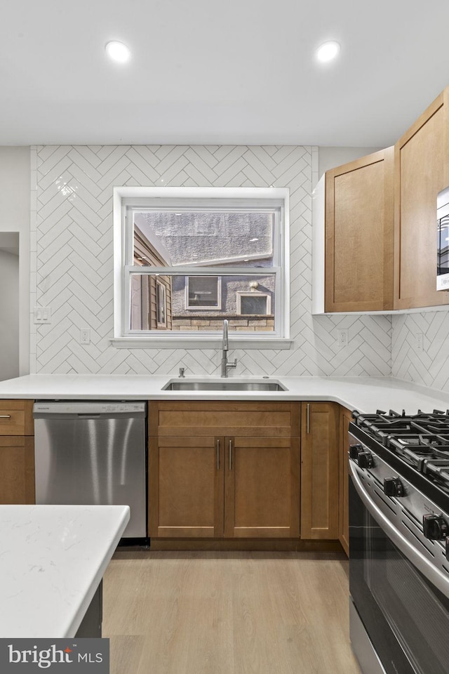 kitchen with sink, backsplash, light hardwood / wood-style flooring, and appliances with stainless steel finishes