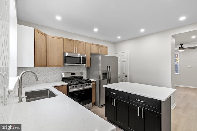 kitchen with light brown cabinetry, sink, backsplash, stainless steel appliances, and light hardwood / wood-style flooring