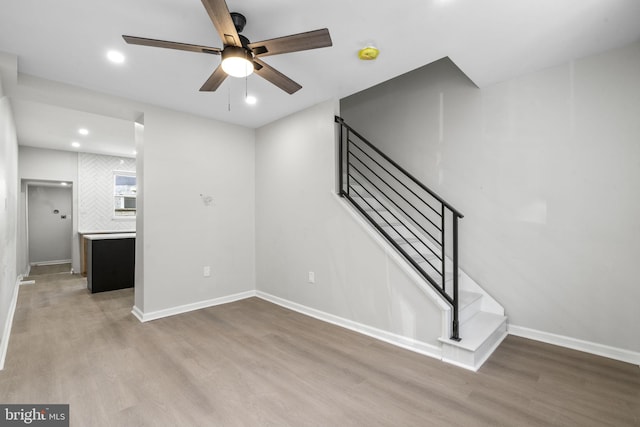 stairway with hardwood / wood-style floors and ceiling fan