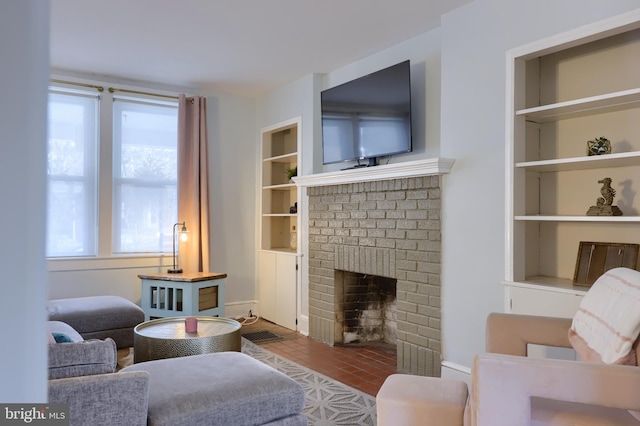 living room featuring built in shelves and a brick fireplace