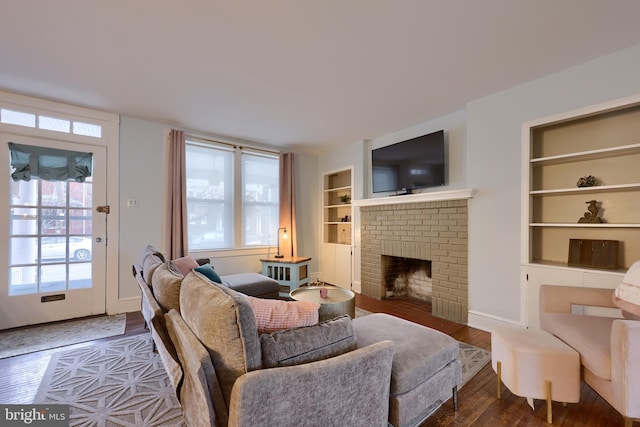 living room with a brick fireplace, built in shelves, and wood-type flooring