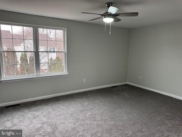 spare room featuring ceiling fan and dark carpet