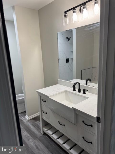 bathroom featuring hardwood / wood-style flooring, vanity, toilet, and a shower