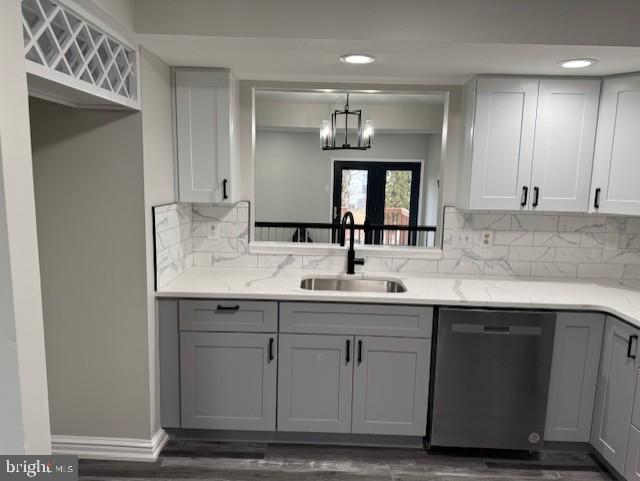 kitchen with dishwashing machine, sink, gray cabinetry, light stone counters, and decorative backsplash