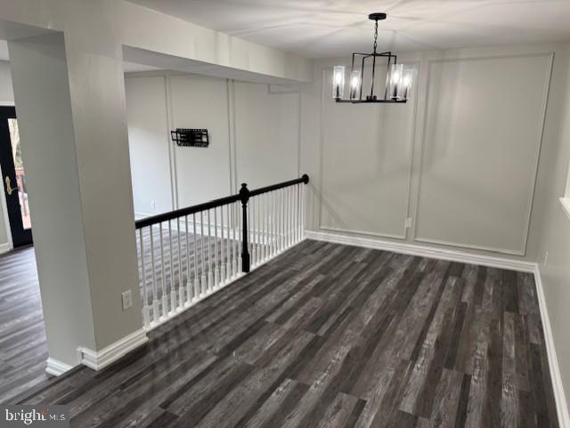 unfurnished dining area featuring a notable chandelier and dark hardwood / wood-style floors