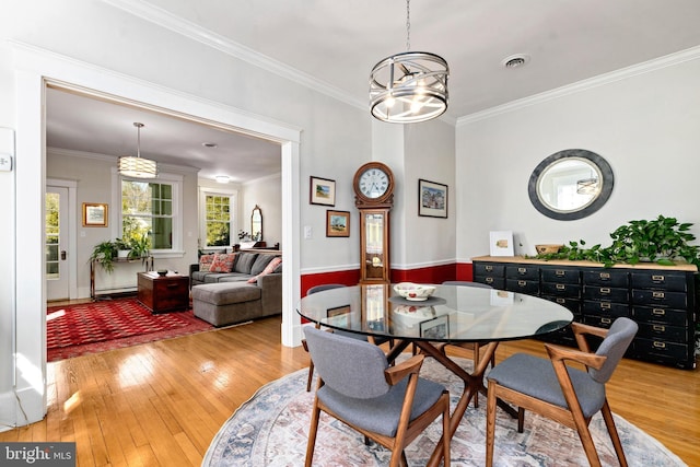 dining room with ornamental molding, a chandelier, visible vents, and light wood-style flooring