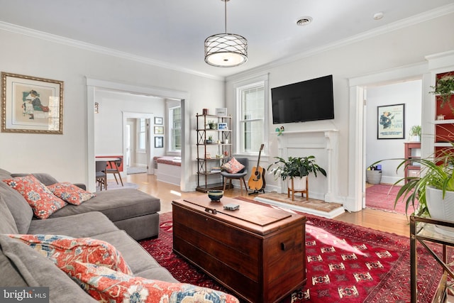 living area with a healthy amount of sunlight, visible vents, crown molding, and a fireplace with raised hearth