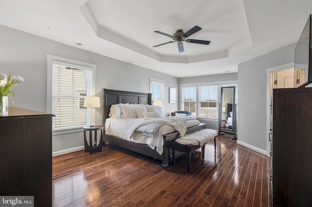 bedroom featuring a raised ceiling, dark hardwood / wood-style floors, and ceiling fan