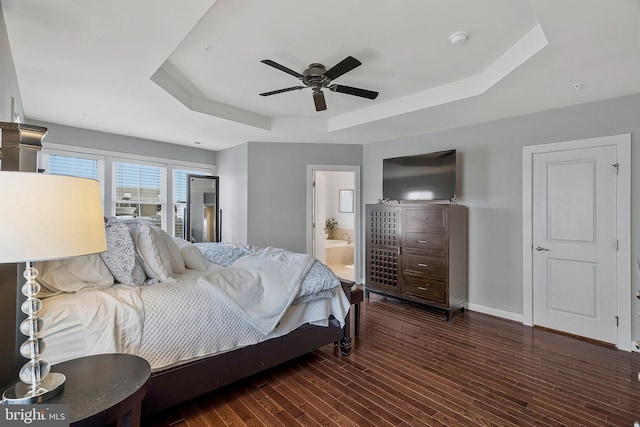 bedroom featuring dark wood-type flooring, a raised ceiling, ceiling fan, and ensuite bathroom