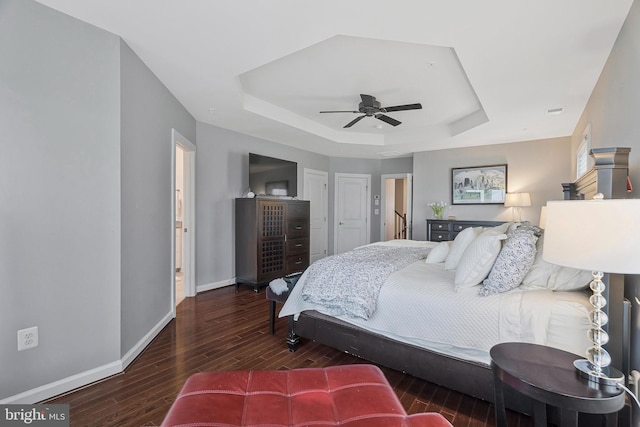 bedroom featuring ceiling fan, a tray ceiling, and dark hardwood / wood-style flooring