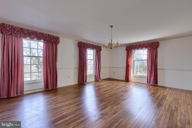 unfurnished room with a healthy amount of sunlight, a notable chandelier, dark hardwood / wood-style flooring, and baseboard heating