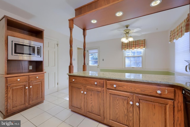 kitchen featuring light tile patterned flooring, stainless steel microwave, black dishwasher, ceiling fan, and light stone countertops