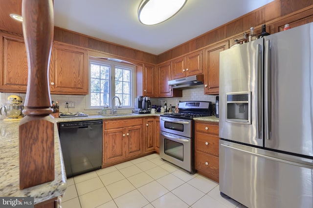 kitchen with sink, appliances with stainless steel finishes, tasteful backsplash, light stone countertops, and light tile patterned flooring