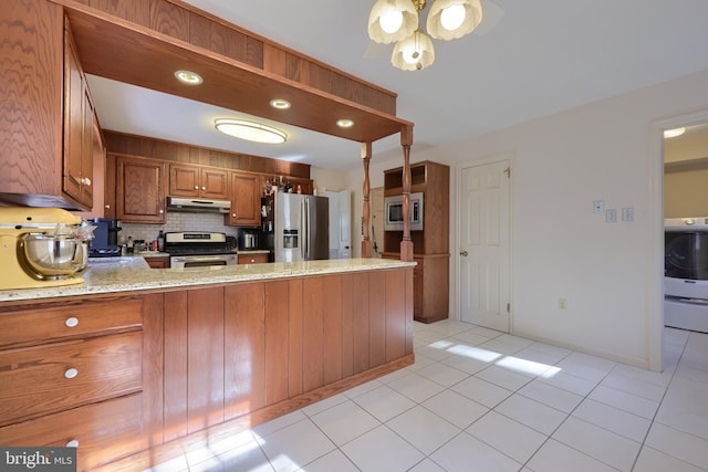 kitchen with light stone counters, washer / dryer, stainless steel appliances, and kitchen peninsula