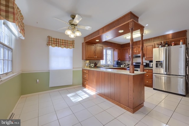 kitchen featuring light tile patterned floors, sink, appliances with stainless steel finishes, a baseboard radiator, and kitchen peninsula