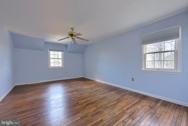 empty room featuring vaulted ceiling, dark hardwood / wood-style floors, ceiling fan, and baseboard heating