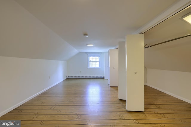 additional living space with a baseboard radiator, lofted ceiling, and light hardwood / wood-style floors