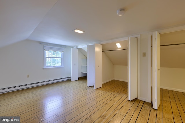 additional living space featuring vaulted ceiling, a baseboard heating unit, and light hardwood / wood-style flooring