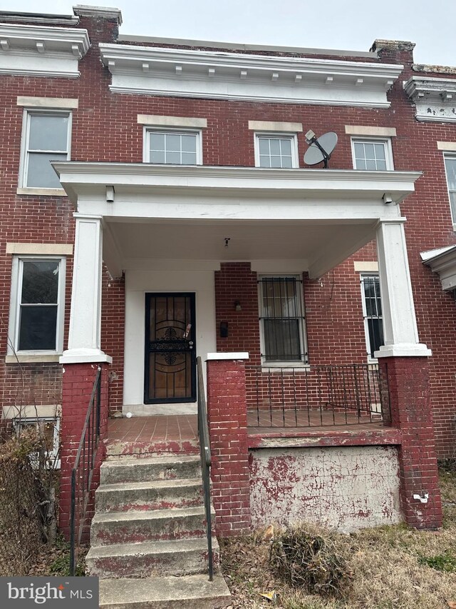 multi unit property with brick siding and a porch