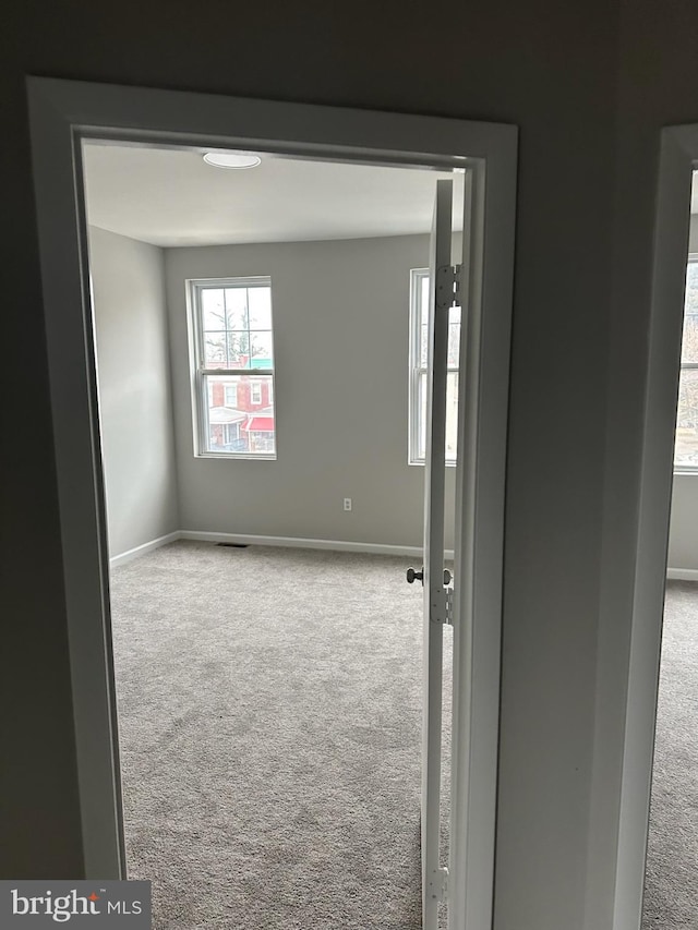 carpeted empty room with visible vents and baseboards