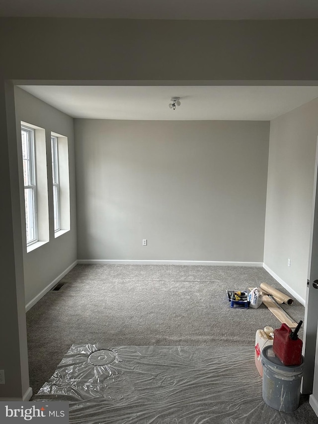 carpeted empty room with visible vents and baseboards