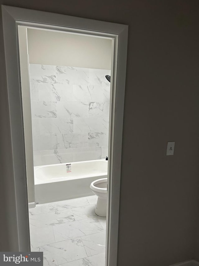 full bathroom with washtub / shower combination, marble finish floor, and toilet