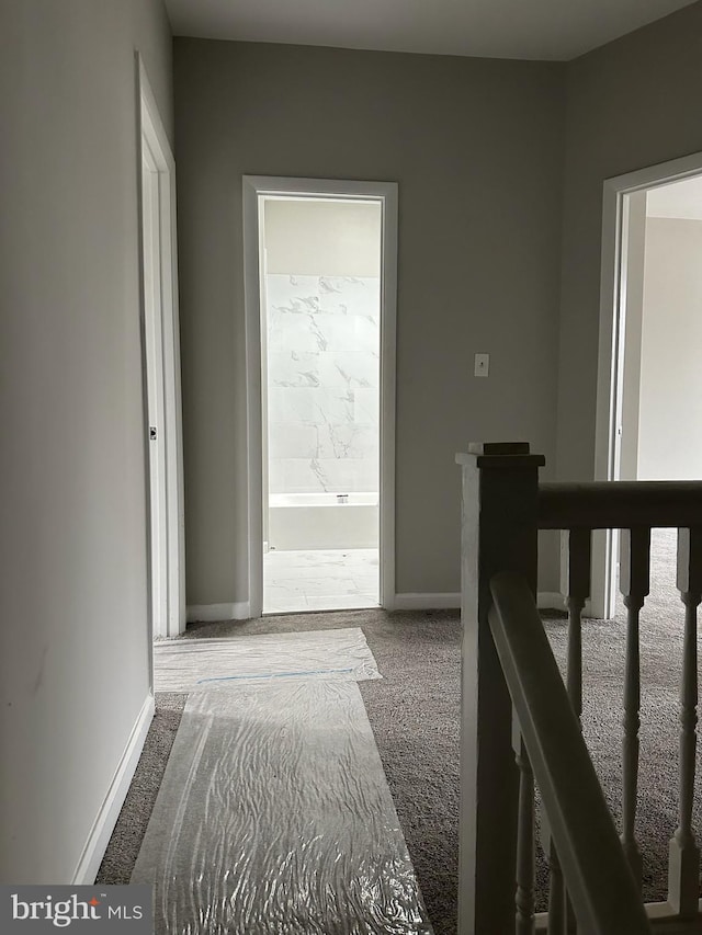 corridor with carpet floors, baseboards, and an upstairs landing