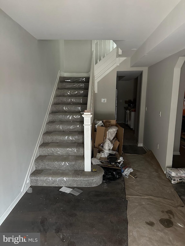 staircase featuring arched walkways and baseboards