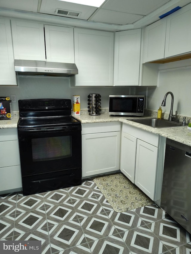 kitchen with light stone counters, sink, black appliances, and white cabinets