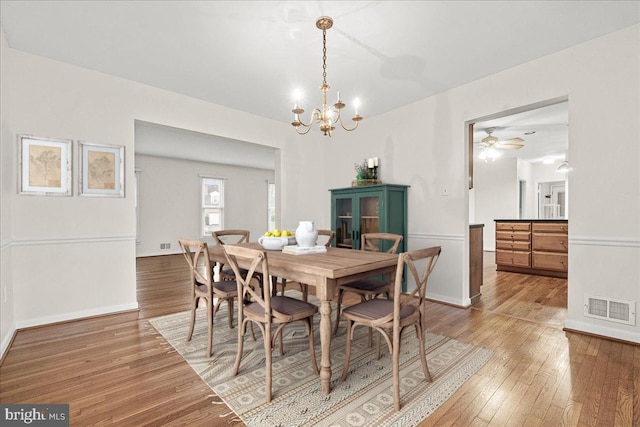 dining area featuring a notable chandelier, hardwood / wood-style floors, visible vents, and baseboards