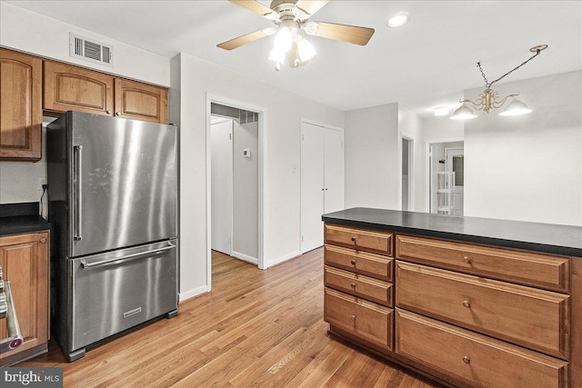 kitchen with dark countertops, light wood-style floors, brown cabinetry, and freestanding refrigerator