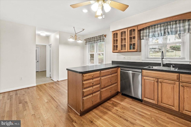 kitchen with brown cabinetry, dark countertops, a sink, and stainless steel dishwasher