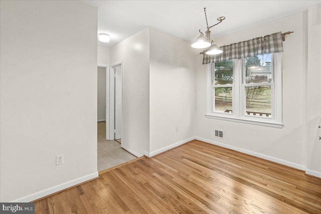 unfurnished dining area featuring wood finished floors, visible vents, and baseboards