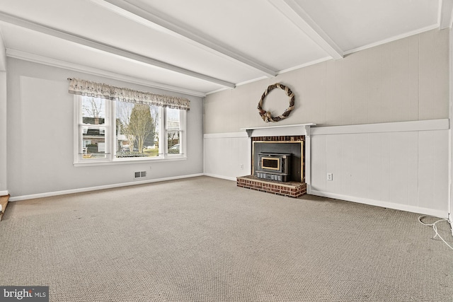 unfurnished living room featuring carpet, visible vents, beam ceiling, and ornamental molding