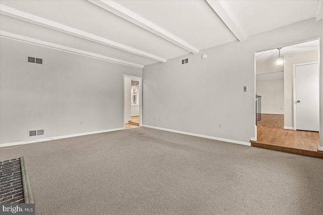 carpeted empty room with baseboards, visible vents, and beamed ceiling