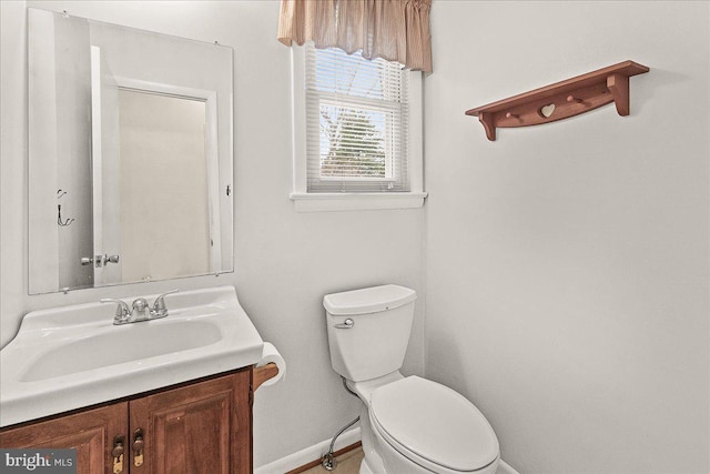 half bathroom featuring baseboards, vanity, and toilet