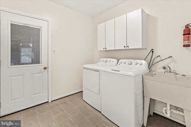 laundry area with washing machine and dryer, cabinet space, a sink, and baseboards