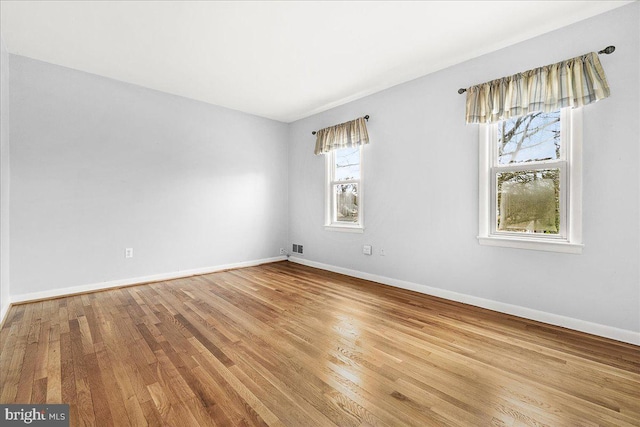 spare room with baseboards and wood finished floors