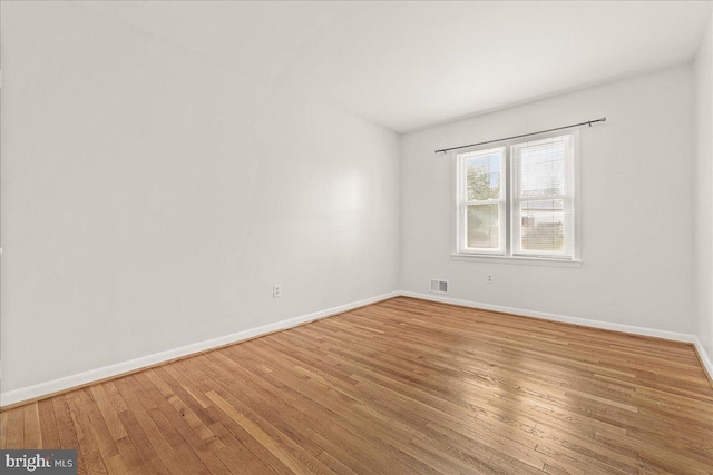 unfurnished room featuring visible vents, baseboards, and hardwood / wood-style flooring