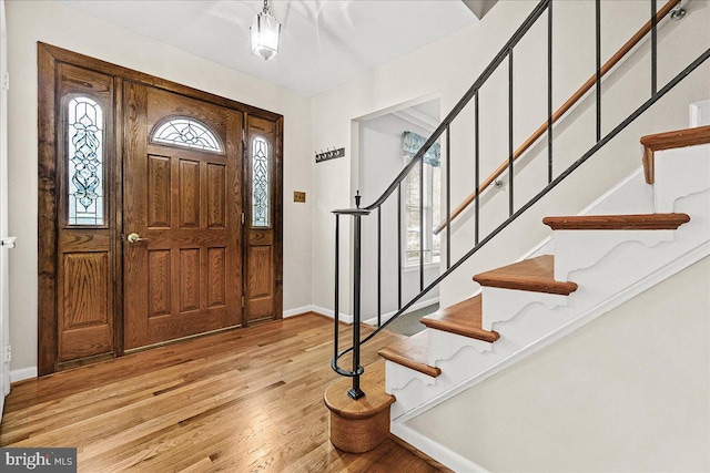 foyer entrance featuring stairs, wood finished floors, a wealth of natural light, and baseboards